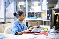 Woman in office workspace using a computer focused on work tasks.
