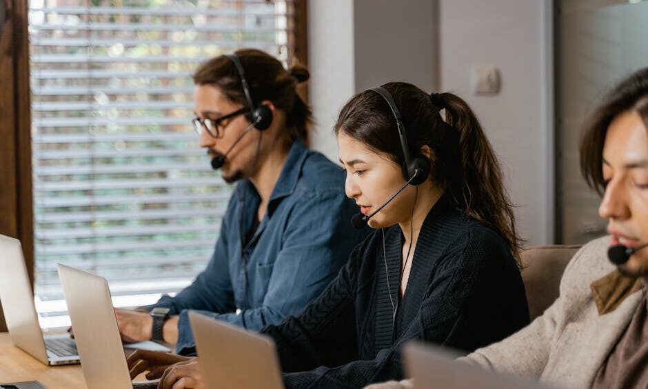 Team of professionals in a call center providing customer support using laptops and headsets.