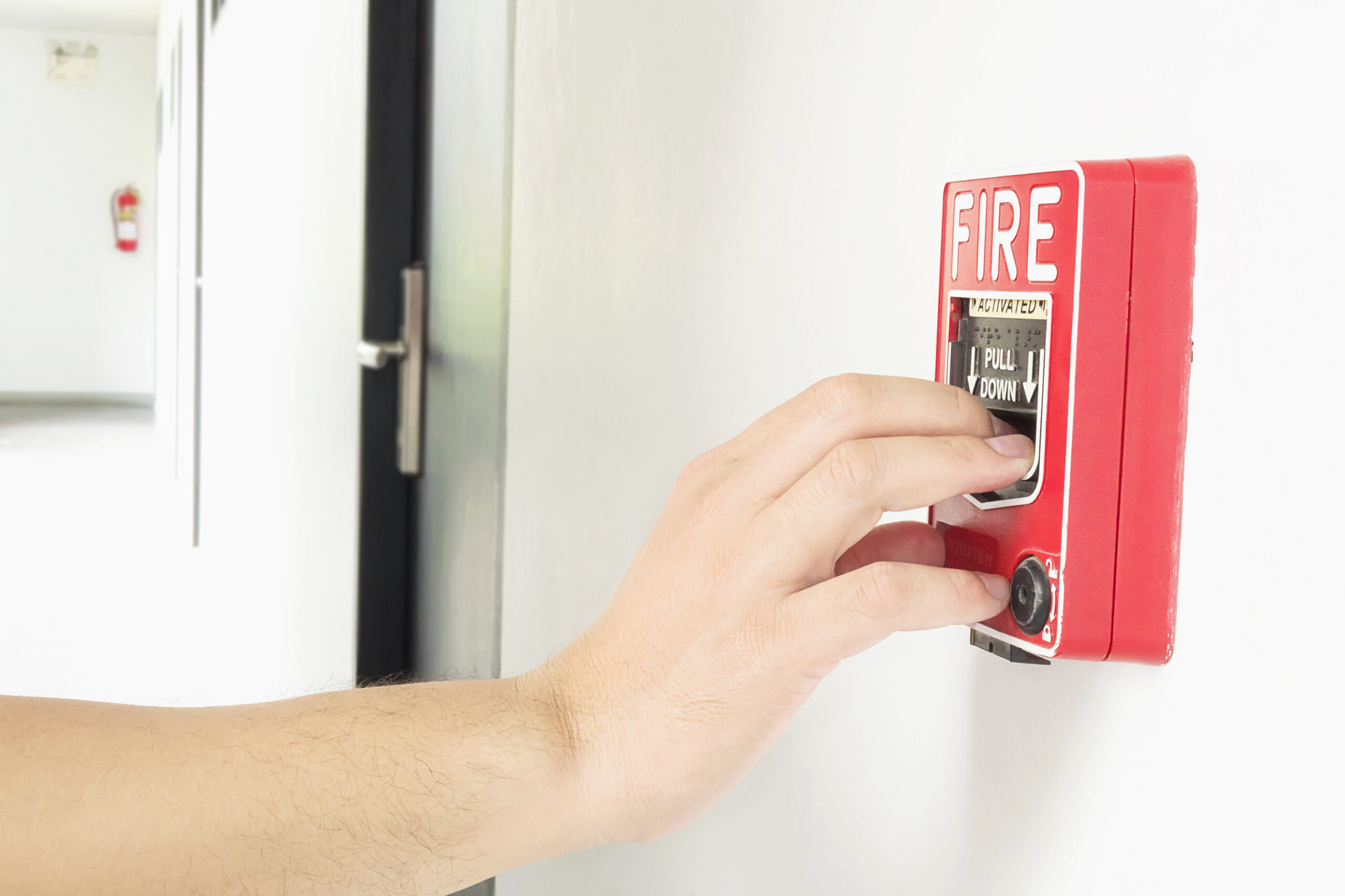 man is reaching his hand to push fire alarm hand station
